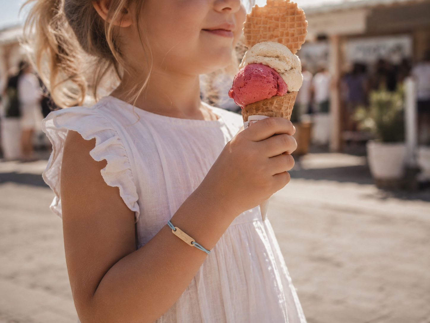 Enfant souriant avec une glace lors d'une sortie, bracelet Bobiin au poignet